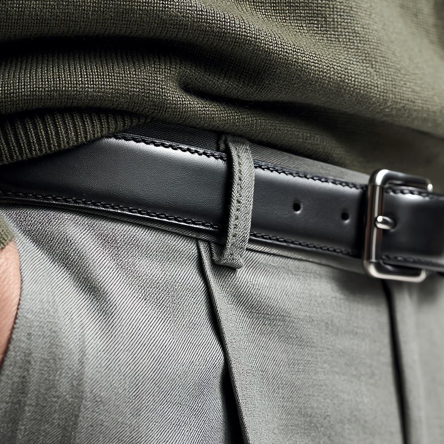 Black leather belt with a silver buckle worn with grey trousers