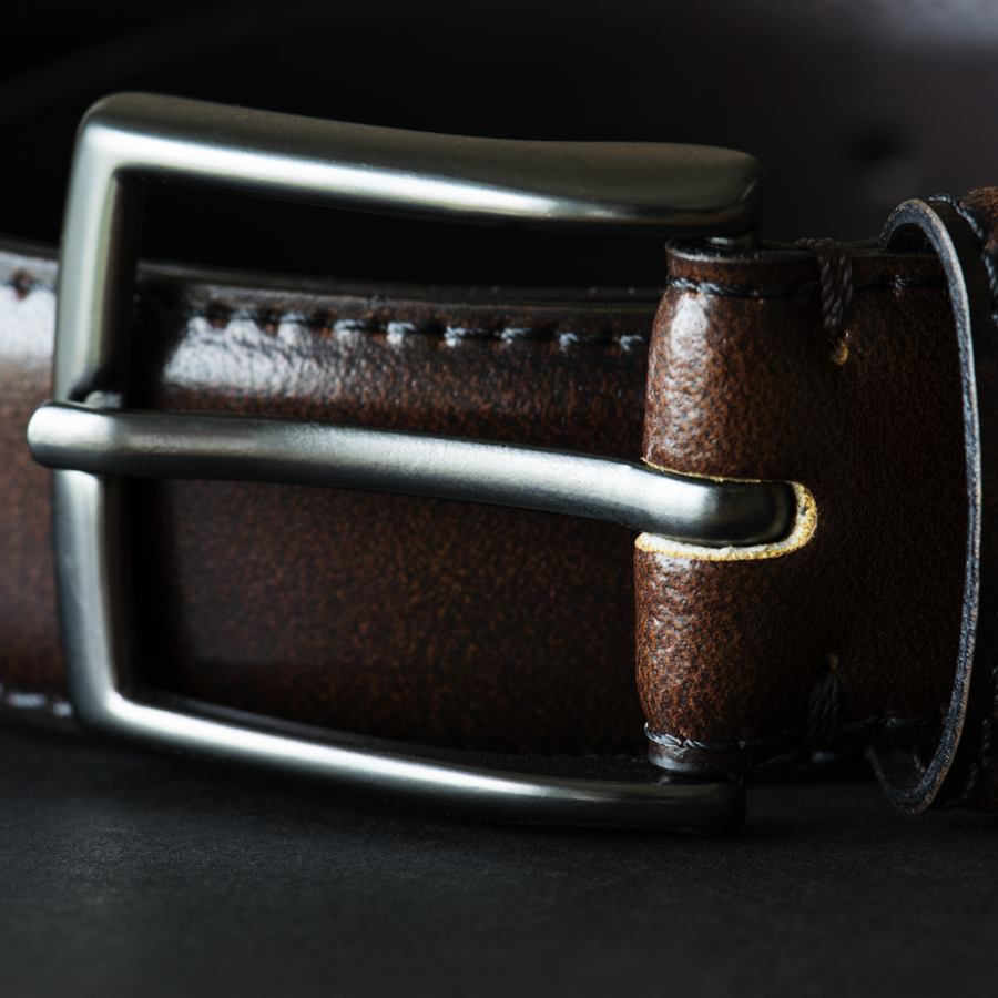 Close-up of a brown leather belt with a dark metal buckle and stitched edges
